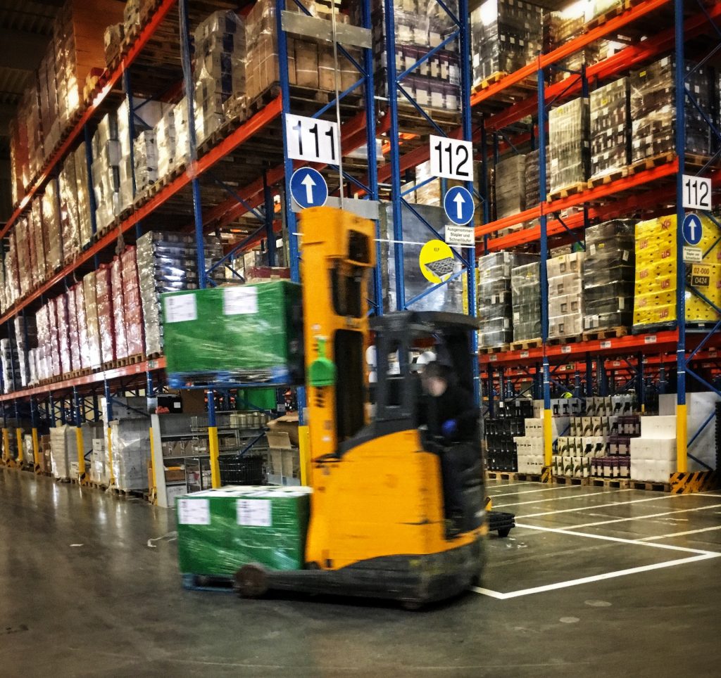 a forklift driving through a warehouse filled with pallets